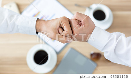 Top view of two men touch knuckles hands, Businessman fist bump hand after success meeting talk, Fist bump friends deal partner, Businessman and partner fist bumping hand. Top view of two men touch knuckles hands, Businessman fist bump hand after success meeting talk, Fist bump friends deal partner, Businessman and partner fist bumping hand. 98301126