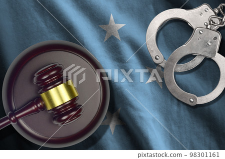 Micronesia flag with judge mallet and handcuffs in dark room. Concept of criminal and punishment, background for judgement topics Micronesia flag with judge mallet and handcuffs in dark room. Concept of criminal and punishment, background for judgement topics 98301161
