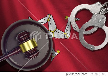 Isle of Man flag with judge mallet and handcuffs in dark room. Concept of criminal and punishment, background for judgement topics Isle of Man flag with judge mallet and handcuffs in dark room. Concept of criminal and punishment, background for judgement topics 98301183