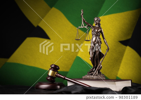 Jamaica flag with statue of lady justice, constitution and judge hammer on black drapery. Concept of judgement and guilt 98301189
