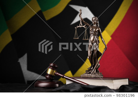 Saint Kitts and Nevis flag with statue of lady justice, constitution and judge hammer on black drapery. Concept of judgement and guilt Saint Kitts and Nevis flag with statue of lady justice, constitution and judge hammer on black drapery. Concept of judgement and guilt 98301196