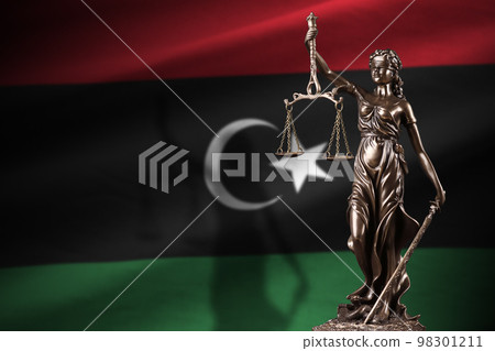 Libya flag with statue of lady justice and judicial scales in dark room. Concept of judgement and punishment Libya flag with statue of lady justice and judicial scales in dark room. Concept of judgement and punishment 98301211