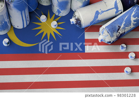 Malaysia flag and few used aerosol spray cans for graffiti painting. Street art culture concept Malaysia flag and few used aerosol spray cans for graffiti painting. Street art culture concept 98301228