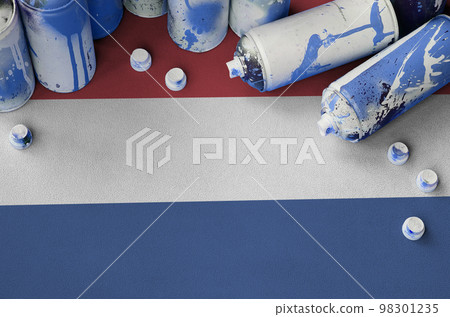 Netherlands flag and few used aerosol spray cans for graffiti painting. Street art culture concept 98301235