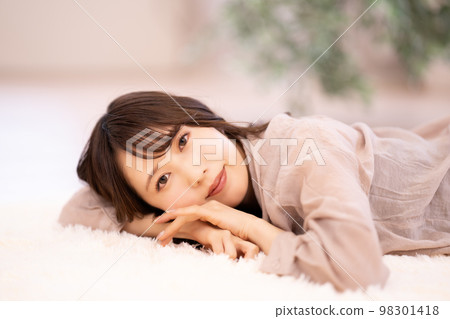 Young woman lying on the carpet and relaxing Young woman lying on the carpet and relaxing 98301418