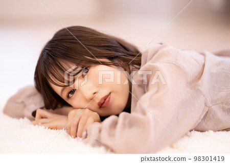 Young woman lying on the carpet and relaxing Young woman lying on the carpet and relaxing 98301419