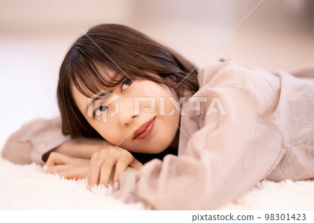 Young woman lying on the carpet and relaxing Young woman lying on the carpet and relaxing 98301423