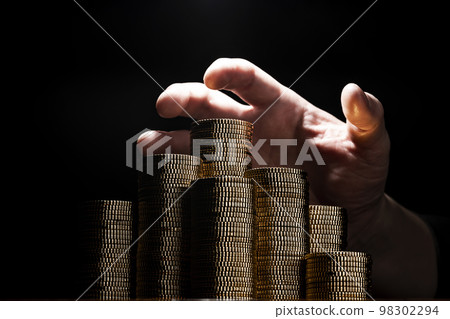 Male hand grabbing a gold coin Male hand grabbing a gold coin 98302294
