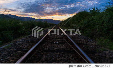 A beautiful sunset in the background of the railroad tracks and the scenery of the Aso mountains "Minami Aso Shirakawa Suigen Station" 98303677