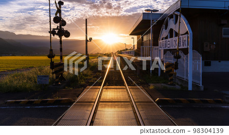 A beautiful sunset in the background of the railroad tracks and the scenery of the Aso mountains "Minami Aso Shirakawa Suigen Station" 98304139