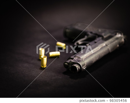 Handgun with 9mm shell casings on black background Handgun with 9mm shell casings on black background 98305456