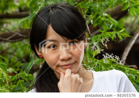 Dutch angle portrait of Asian woman standing in front of trees Dutch angle portrait of Asian woman standing in front of trees 98305576