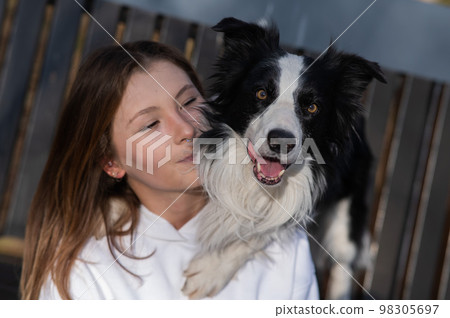 Caucasian woman hugging her dog Border Collie while sitting on a bench in autumn park. Caucasian woman hugging her dog Border Collie while sitting on a bench in autumn park. 98305697