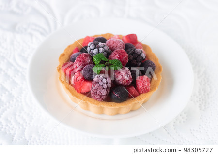 Cream cheese tart topped with frozen berries 98305727