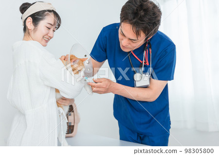 A cat being examined by a veterinarian at an animal hospital and its owner, an Asian woman (pet Elizabeth Collar) 98305800