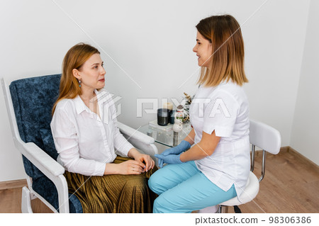 Consultation in cosmetology clinic. Beautician examining face skin 98306386