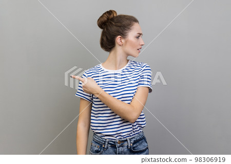 Get out. Portrait of woman annoyed young adult in striped T-shirt turning away and asking to leave her, showing exit, feeling betrayed and resentful. Indoor studio shot isolated on gray background. Get out. Portrait of woman annoyed young adult in striped T-shirt turning away and asking to leave her, showing exit, feeling betrayed and resentful. Indoor studio shot isolated on gray background. 98306919