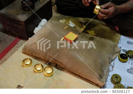 Putting gold leaf on Mingarabar, a folk craft from Bagan, Myanmar 98308127