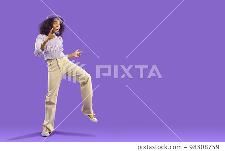 Smiling teen girl dancing on violet background 98308759
