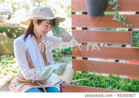 A woman watering the flowers of the gardening fence in the garden (gardening) 98308807