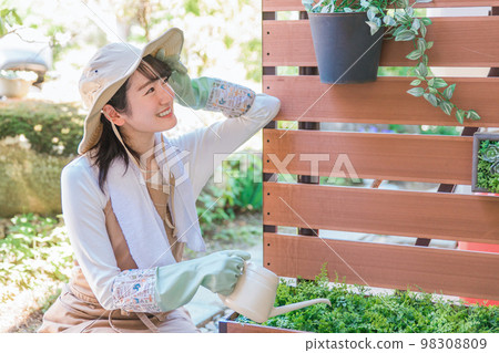 A woman watering the flowers of the gardening fence in the garden (gardening) 98308809