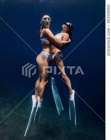 Woman freedivers glides in deep ocean. Freediving with couple girls in underwater 98309060