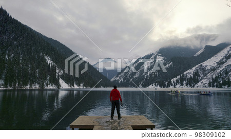 The guy standing on the pier admires mountain lake 98309102