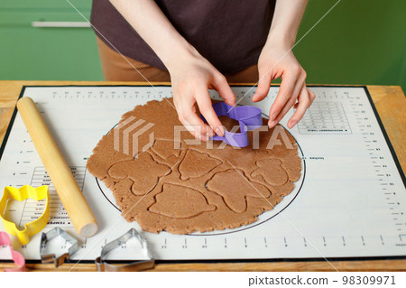 A woman prepares christmas homemade cookies on a silicone baking mat 98309971