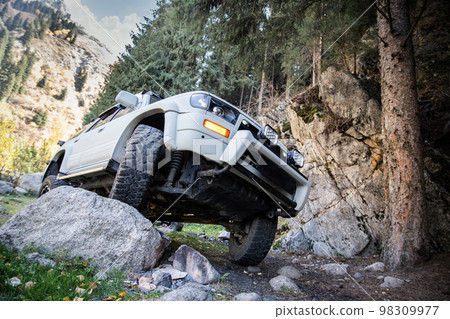 Car upgrade suspension system of a 4x4 suv. Prepared Offroader overcomes natural obstacles on a mountain road lifestyle Car upgrade suspension system of a 4x4 suv. Prepared Offroader overcomes natural obstacles on a mountain road lifestyle 98309977