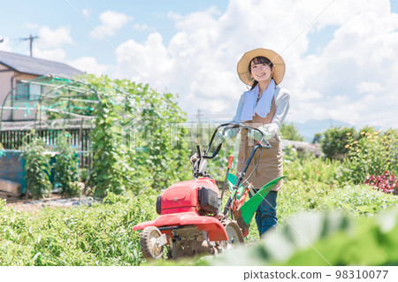 A farmer's Asian woman who plows a field with a small tractor (agriculture) A farmer's Asian woman who plows a field with a small tractor (agriculture) 98310077