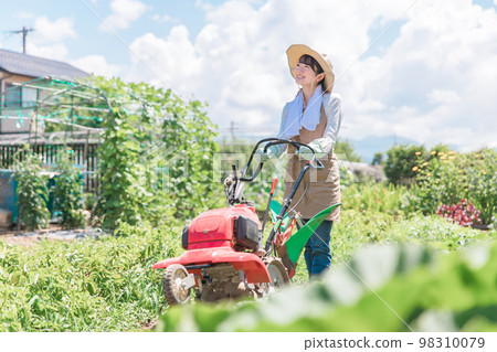 Asian female farmer plowing the field with a small tractor (agriculture) Asian female farmer plowing the field with a small tractor (agriculture) 98310079