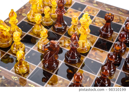 Natural amber different chess pieces figures standing on brown stone board. Close up game concept competition, Classic Gambit Tournament of confrontation. 98310199