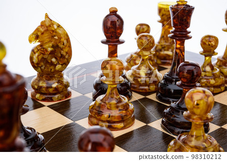 Natural amber different chess pieces figures standing on brown stone board. Close up game concept competition, Classic Gambit Tournament of confrontation. Natural amber different chess pieces figures standing on brown stone board. Close up game concept competition, Classic Gambit Tournament of confrontation. 98310212