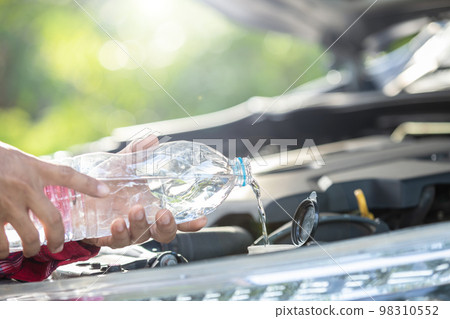 Man refill water to tank of car windshield wiper and checking up the engine before start the trip. Car maintenance or check up concept Man refill water to tank of car windshield wiper and checking up the engine before start the trip. Car maintenance or check up concept 98310552