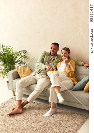 Happy Couple Watching TV At Home. Loving People Resting Sofa And Eating Popcorn 98311417
