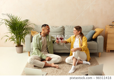Happy Couple Drinking Wine. Smiling Spouses Holding Wineglasses at Home 98311418