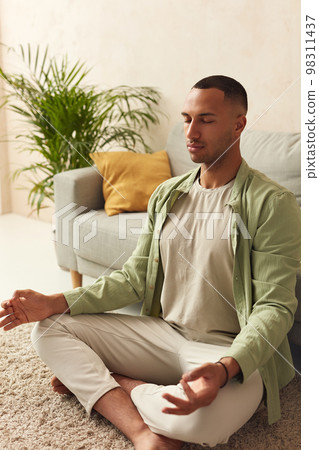 Calm Man Meditating Home. Multiracial Guy Sitting In Lotus Pose Practicing Yoga Calm Man Meditating Home. Multiracial Guy Sitting In Lotus Pose Practicing Yoga 98311437