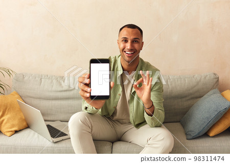 Man Showing Smartphone At Home. Guy Demonstrating Mobile With Blank White Screen 98311474