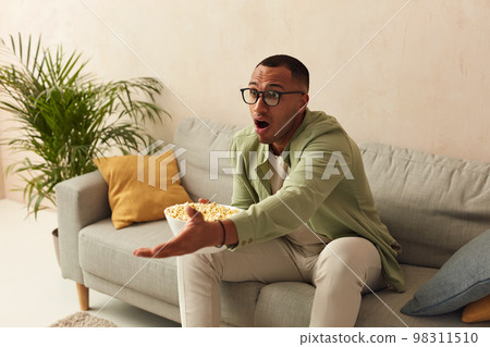 Emotional Man Watching Movie. Multiracial Guy Eating Popcorn, Gesturing Hand Emotional Man Watching Movie. Multiracial Guy Eating Popcorn, Gesturing Hand 98311510