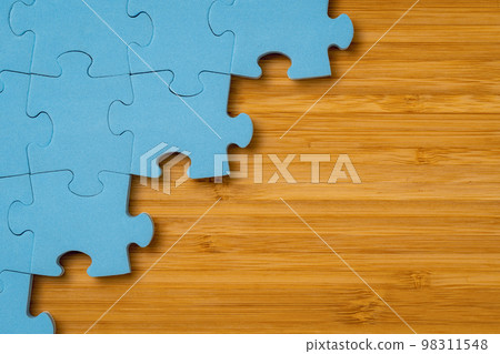 Blue puzzle on wooden background with a copy space 98311548