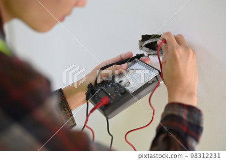 Electrician installing electric cable wires and testing power line current in an electrical system 98312231