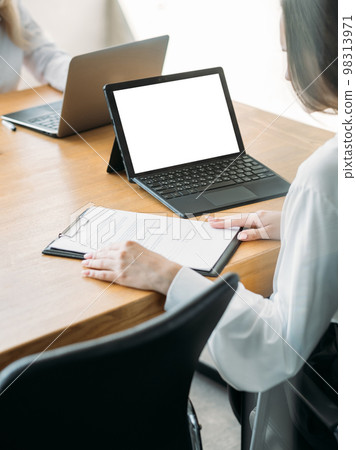Office manager. Working woman. Computer mockup. Unrecognizable lady studying documents sitting desk with laptop blank screen in light room interior. Office manager. Working woman. Computer mockup. Unrecognizable lady studying documents sitting desk with laptop blank screen in light room interior. 98313971