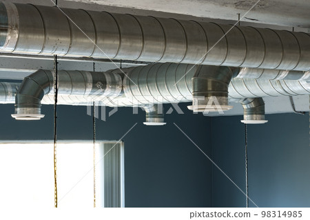 Silver ventilation pipes hanging from the ceiling inside the building 98314985