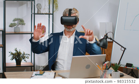 Mature business man in VR goggles watch virtual reality video, working on simulation game at office 98315532