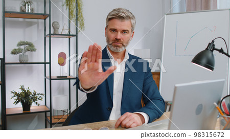 Businessman working on laptop showing stop gestuge, danger, rejection, warning, crisis, prohibition Businessman working on laptop showing stop gestuge, danger, rejection, warning, crisis, prohibition 98315672