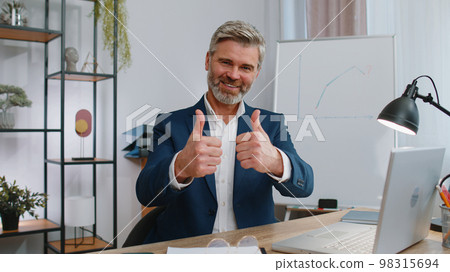 Happy business man looking approvingly at camera showing thumbs up, like positive sign, good news Happy business man looking approvingly at camera showing thumbs up, like positive sign, good news 98315694