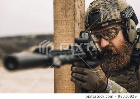 Bearded sniper with optical rifle shooting 98316929
