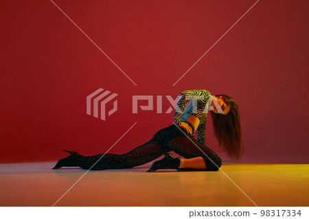 Portrait of young girl dancing heels dance in stylish clothes over red background in neon light. Concept of modern dance style Portrait of young girl dancing heels dance in stylish clothes over red background in neon light. Concept of modern dance style 98317334