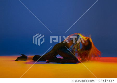 Portrait of young girl dancing heels dance in stylish clothes over blue background in neon with mixed lights. Concept of modern dance style 98317337
