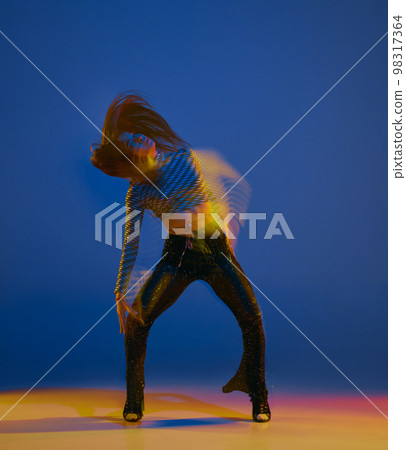 Dynamics. Portrait of young girl dancing heels dance over blue background in neon light with mixed lights. Concept of modern dance style 98317364